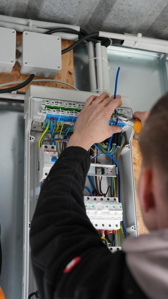 Elektriker verdrahtet den geöffneten Zählerschrank