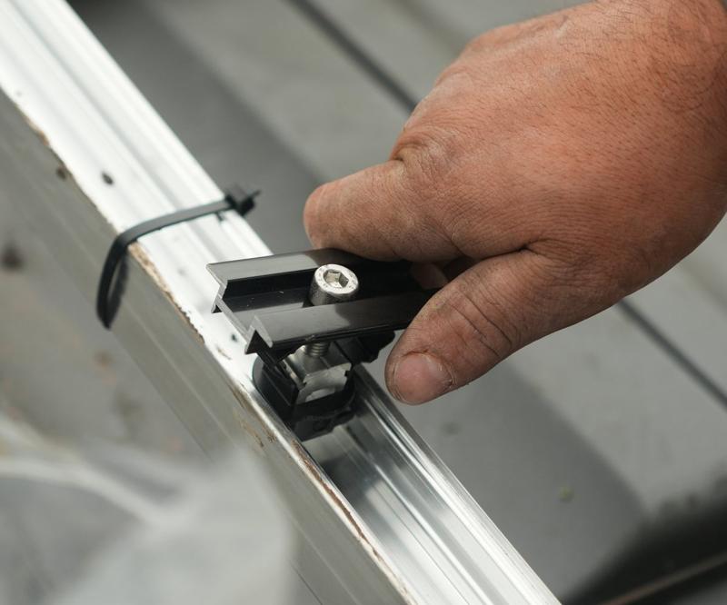 Hand setzt eine Modulklemme auf die Montageschiene