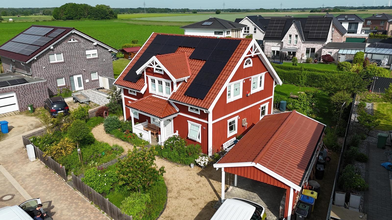 Rotes Schwedenhaus mit vollflächig belegtem Photovoltaikdach aus der Luft