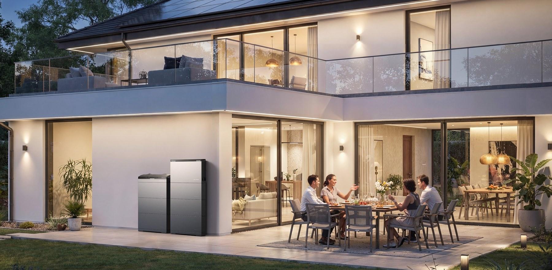 EcoFlow OCEAN 2 an der Außenwand eines Wohnhauses, im Hintergrund eine Familie beim Abendessen auf der Terrasse