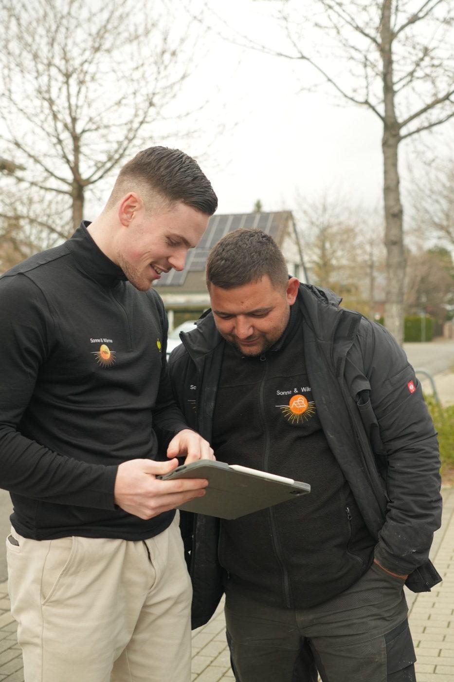 Zwei Mitarbeiter nehmen beim Aufmaß gemeinsam Daten auf dem Tablet auf
