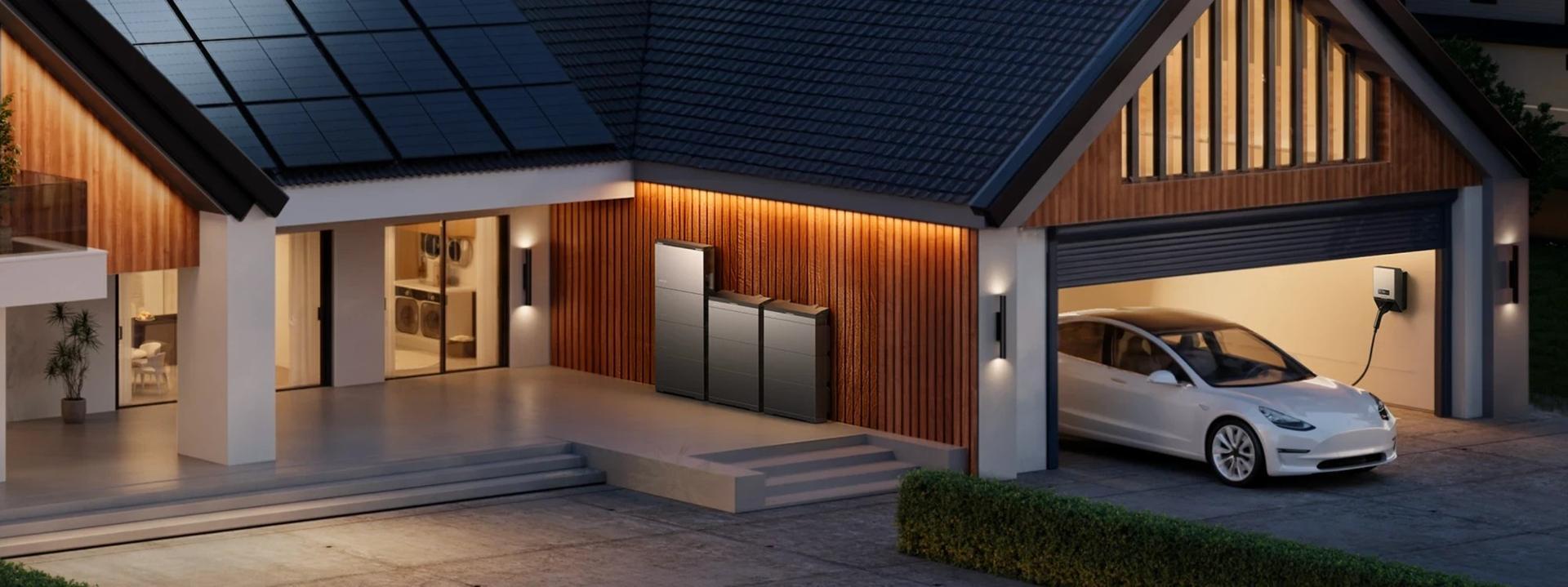 Wohnhaus mit Photovoltaikdach, Stromspeicher an der Hauswand und E-Auto an der Wallbox in der Garage
